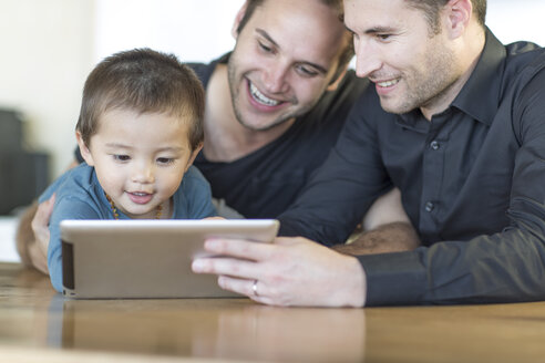 Two men with kid looking at digital tablet - ZEF004438