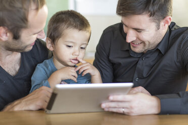 Zwei Männer mit Kind schauen auf ein digitales Tablet - ZEF004439