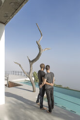 Gay couple standing on a terrace at the poolside - ZEF004298