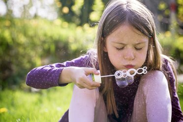 Girl blowing soap bubbles in a garden - SARF001755