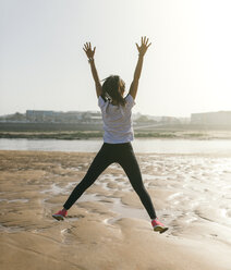 Spain, Gijon, young woman jumping on the beach - MGOF000204