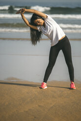 Spain, Gijon, young woman stretching on the beach - MGOF000210