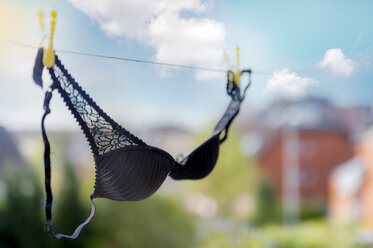 Yellow bra hanging on bent nail in front of wallpaper with pink floral  design stock photo