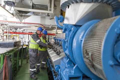 Besatzung bei der Arbeit im Maschinenraum eines Schiffes, lizenzfreies Stockfoto