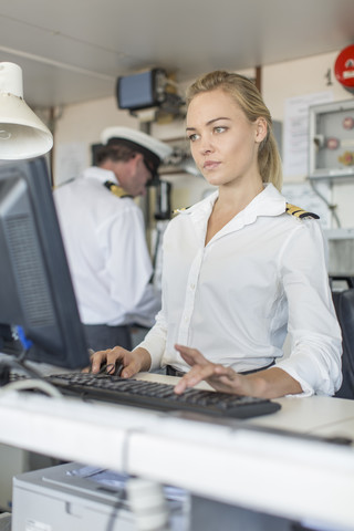 Weiblicher Deckoffizier auf der Brücke am Computer, lizenzfreies Stockfoto