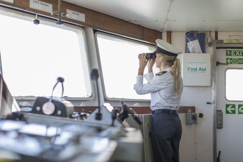 Deck officer on ship looking through binoculars stock photo