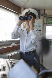 Deck officer on ship looking through binoculars - ZEF005488