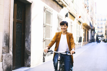Spain, Barcelona, smiling woman with bicycle in the city - EBSF000583