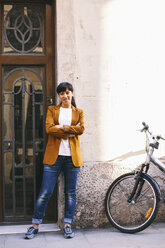 Spanien, Barcelona, Frau mit Fahrrad vor Hauseingang stehend - EBSF000589