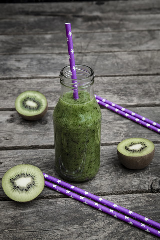 Grüner Smoothie mit Kiwi, Banane und Mache, Trinkhalme, Holz, lizenzfreies Stockfoto