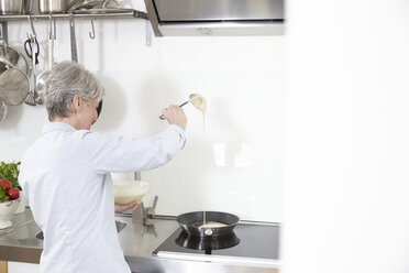 Mature woman in kitchen preparing pancakes - FMKF001452