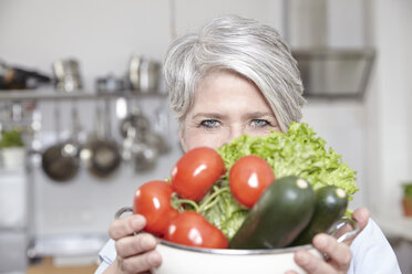 Ältere Frau hält Topf mit Gemüse - FMKF001463
