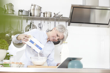 Ältere Frau in der Küche, die Mehl in eine Schüssel gießt - FMKF001471