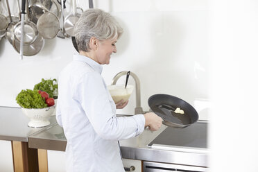Mature woman in kitchen preparing pancakes - FMKF001498