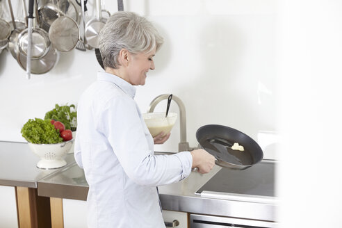 Ältere Frau in der Küche bereitet Pfannkuchen zu - FMKF001498