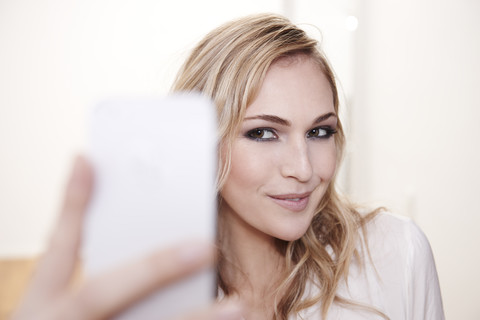 Lächelnde junge Frau nimmt Selfie, lizenzfreies Stockfoto