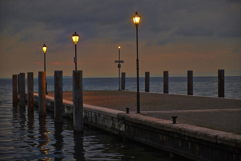 Italien, Garda, Gardasee, Seebrücke mit Laternen am Abend - MRF001623