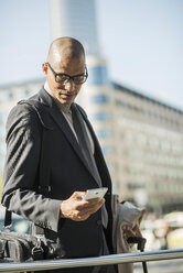 Businessman in the city looking on smartphone - UUF004008