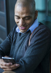 Smiling man outdoors looking on smartphone - UUF004020