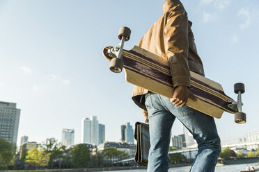 Deutschland, Frankfurt, Mann unterwegs mit Skateboard und Aktentasche - UUF004027