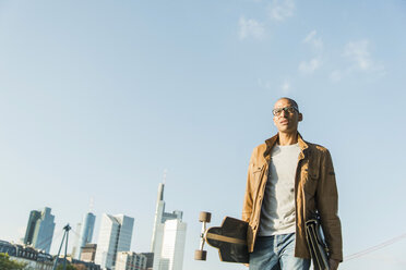 Germany, Frankfurt, man on the go carrying skatebaord and briefcase - UUF004029