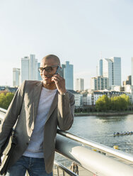 Germany, Frankfurt, businessman on bridge talking on smartphone - UUF004036