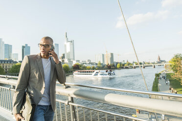 Deutschland, Frankfurt, Geschäftsmann auf Brücke spricht mit Smartphone - UUF004038