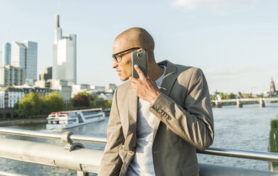 Deutschland, Frankfurt, Geschäftsmann auf Brücke spricht mit Smartphone - UUF004039
