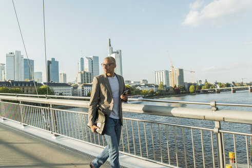 Deutschland, Frankfurt, Geschäftsmann geht auf Brücke - UUF004040