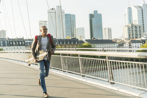 Deutschland, Frankfurt, Mann läuft mit Skateboard auf Brücke, lizenzfreies Stockfoto