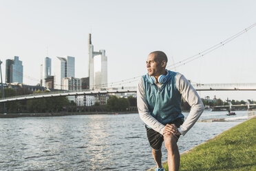 Germany, Frankfurt, man stretching by the riverside - UUF004054