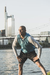 Germany, Frankfurt, man stretching by the riverside - UUF004055