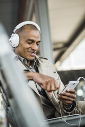 Man wearing headphones holding smartphone - UUF004061
