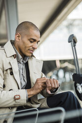 Businessman outdoors checking the time - UUF004062