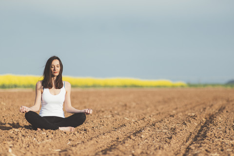 Frau meditiert auf einem Feld, lizenzfreies Stockfoto