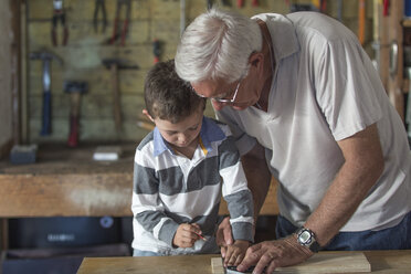 Grandfather and grandson working with wood in a garage - ZEF004602