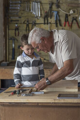 Grandfather and grandson working with wood in a garage - ZEF004608