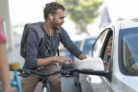 Man on bicycle talking to woman in car stock photo