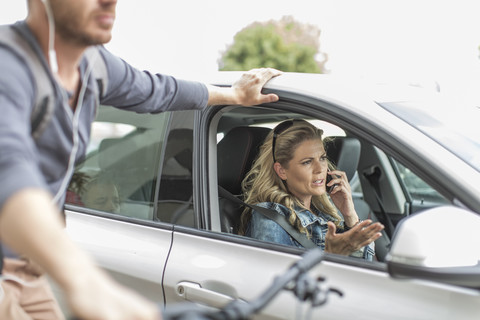 Man on bicycle and woman in car in traffic jam stock photo