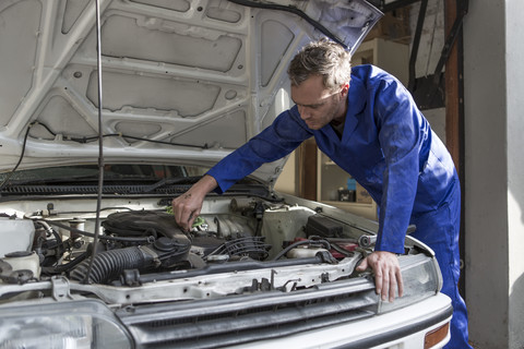 Mann arbeitet an Auto in heimischer Garage, lizenzfreies Stockfoto