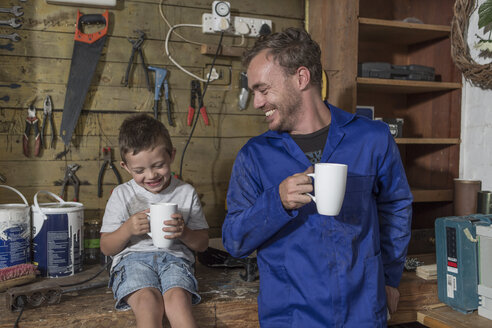 Father and son working in home garage having coffee break - ZEF004821