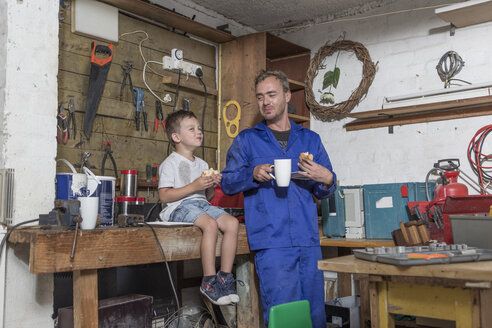 Father and son working in home garage having lunch break - ZEF004908