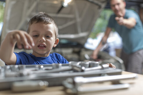 Son helping father in home garage working on car - ZEF004824