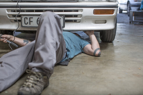 Mechanic lying on floor working on car - ZEF004879