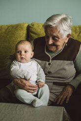 Senior woman with baby boy on her lap at home - RAEF000162