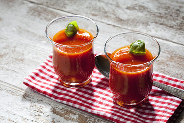 Zwei Gläser Tomatensuppe garniert mit einem Basilikumblatt - CSF025408