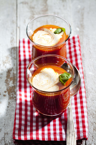 Zwei Gläser Tomatensuppe garniert mit Sahne und Basilikumblatt, lizenzfreies Stockfoto