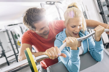 Junges Paar trainiert mit EZ-Curl-Stange im Fitnessstudio - MADF000201