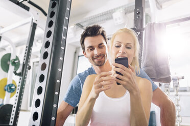 Young couple with smartphone after training at gym - MADF000213