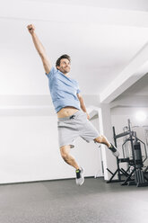 Junger Mann springt im Fitnessstudio in die Luft - MADF000214
